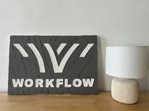 Workflow-Logo reliefartig in weißer Struktur auf grau gespachteltem Untergrund.